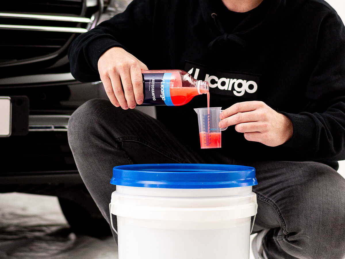 Autoshampoo wird in Messbecher gegeben